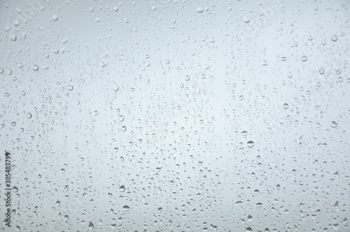 Window with rain droplets and grey sky in background