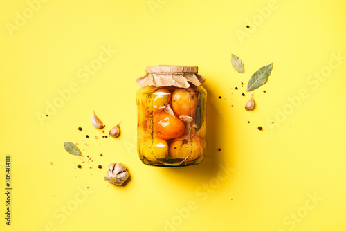 Fotografia Pickled tomatoes in jar on yellow background