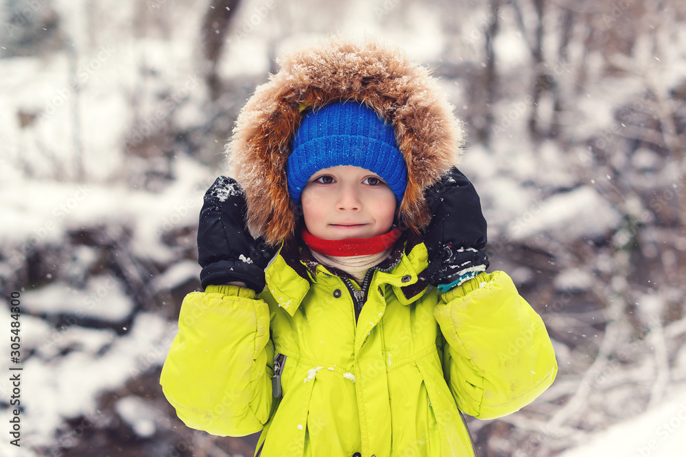 Obraz premium Cute little boy in winter fashion outfit. Child on a winter walk during snowfall. Winter vacation