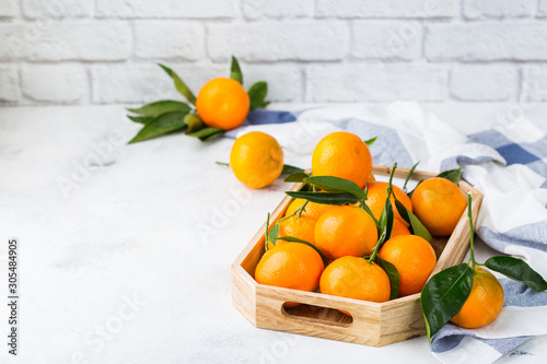 Fresh orange mandarins, tangerines with green leaves on a table © aamulya