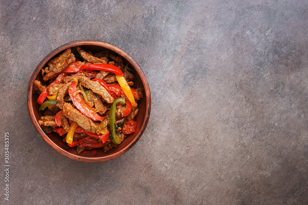 Traditional mexican dish fajitas in a ceramic bowl on a dark rustic background. Top view, flat lay, copy space. Traditional mexican dish fajitas in a ceramic bowl on a dark rustic background. Top view, flat lay, copy space.