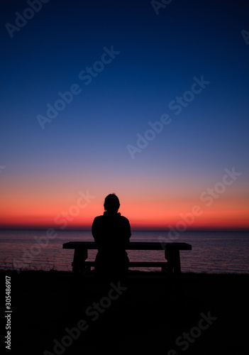 human silhouette relaxed sitting at table at sea in the sunset time