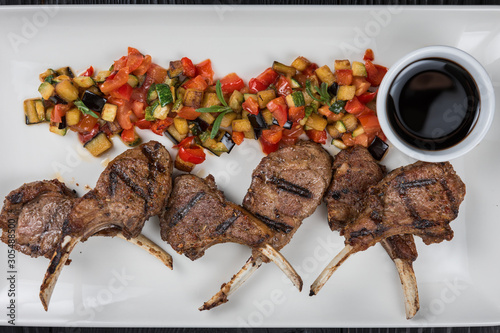 Roasted lamb ribs with vegetables on white palte photo