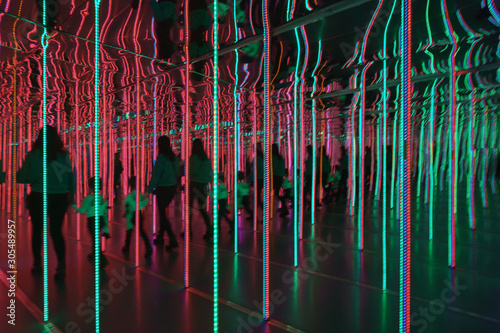 Silhouettes of people among the bright light lines in the mirror maze.