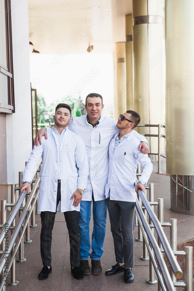 A group of European male medical students presented outdoor against the university door on the steps A group of European male medical students presented outdoor against the university door on the steps