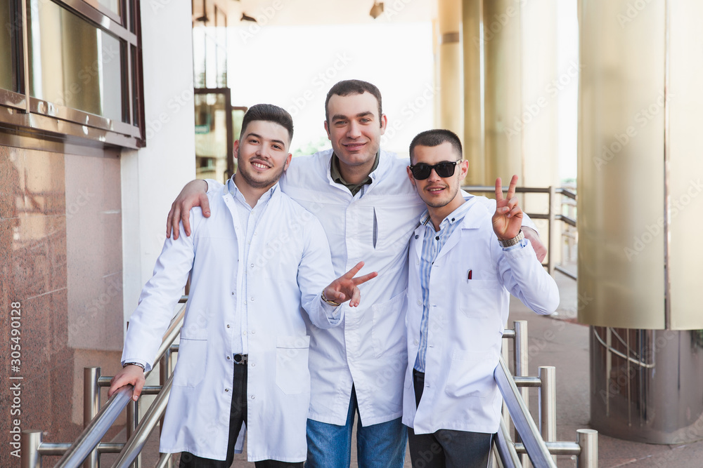 A group of European male medical students presented outdoor against the university door on the steps A group of European male medical students presented outdoor against the university door on the steps