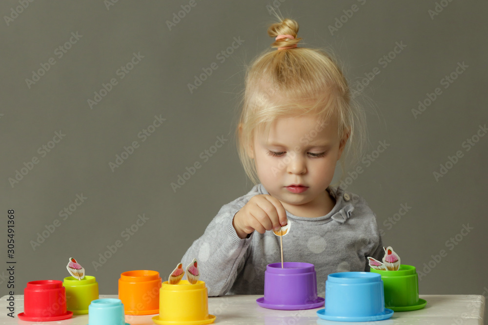 Studio shot of a toddler playing with colorful plastic cups, motor skill development. These activities for toddlers will get little hands and fingers ready for later-developing skills. Studio shot of a toddler playing with colorful plastic cups, motor skill development. These activities for toddlers will get little hands and fingers ready for later-developing skills.