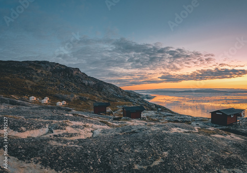 Panoramic image of Camp Eqi at Eqip Sermia Glacier in Greenland. nature landscape with lodge cabins. Midnight sun and pink sky. Tourist destination Eqi glacier in West Greenland AKA Ilulissat and