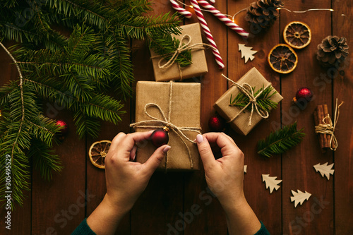 Canvas Print Close-up of female hands packing Christmas gifts on table, top view