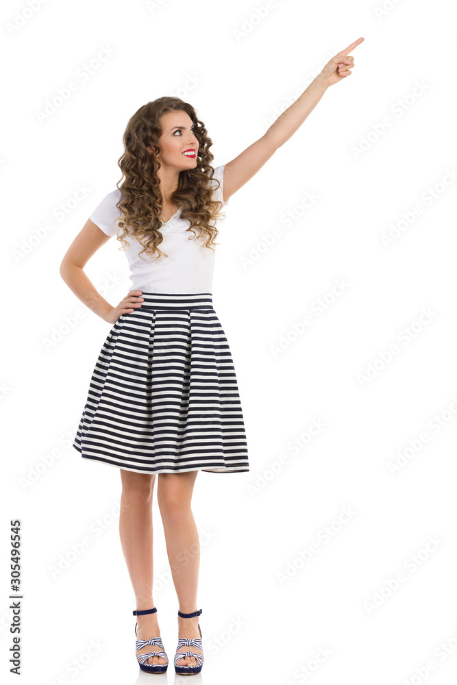 Woman In Striped Skirt And High Heels Is Pointing Up And Looking Away