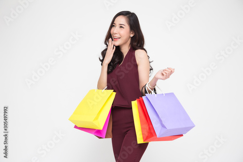 Portrait of a happy young women in red dress holding shopping bags isolated over white background, Year end sale or mid year sale promotion clearence for Shopaholic concept, Asian female model