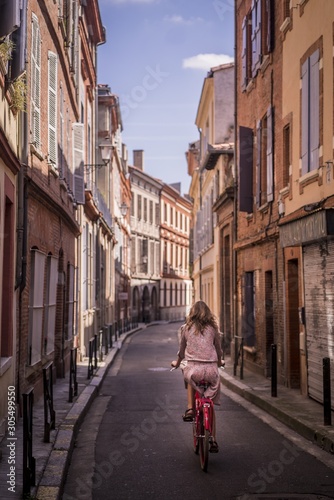 Vertical shot of a female riding a bike in the streets of Toulouse, France