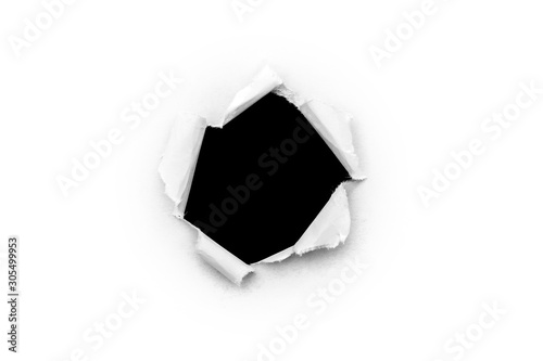 A round hole in white paper with torn edges isolated on a white background with a black isolated background inside.