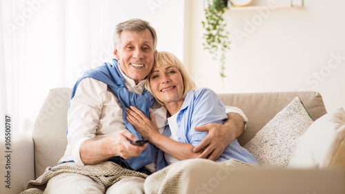 Elderly spouses watching television, man choosing channel