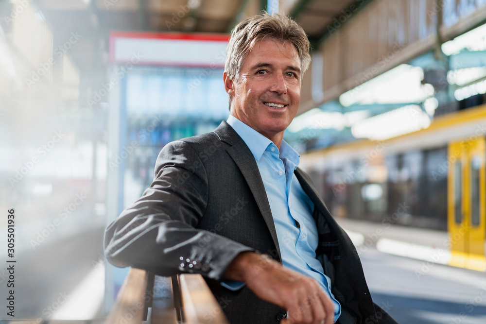 Portrait of smiling mature businessman waiting at station platform Portrait of smiling mature businessman waiting at station platform