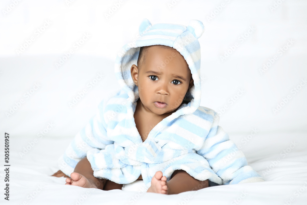 American baby girl in bathrobe sitting on bed American baby girl in bathrobe sitting on bed