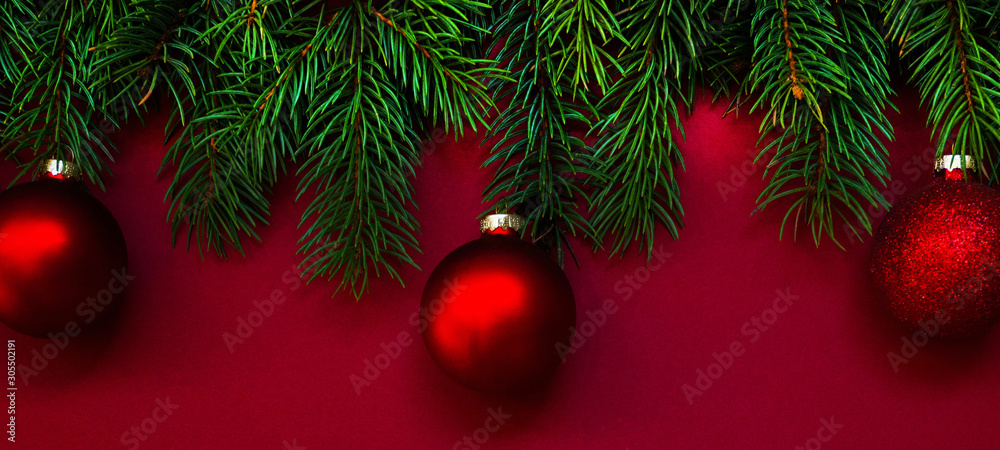 Christmas composition. Fresh fir tree branches, decorations on red background. Christmas, winter, new year concept. Flat lay, top view, copy space.