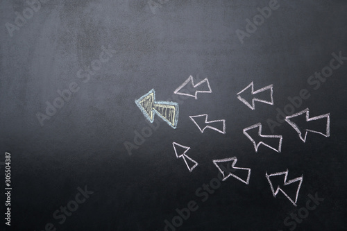 Leader concept. White arrows drawn on blackboard