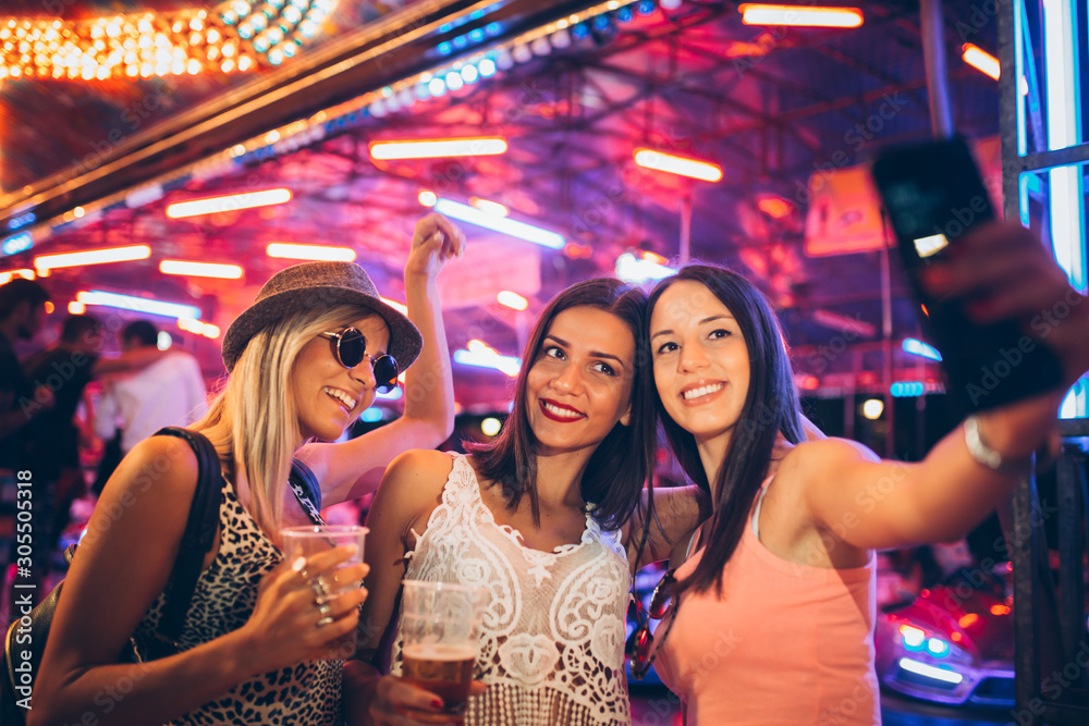Female friends having fun and taking selfie in the amusement park