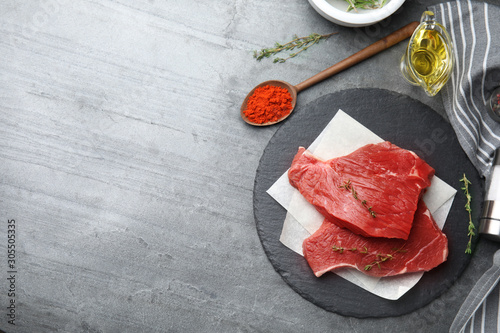 Flat lay composition with fresh beef cut on grey table. Space for text
