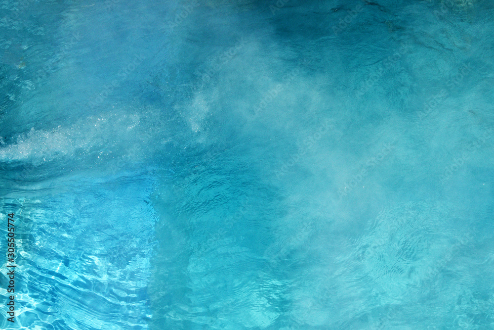 Pure clear water in the thermal pool. Hot water flows and fog rises above the pool, steam. Blue water, beautiful background. Pure clear water in the thermal pool. Hot water flows and fog rises above the pool, steam. Blue water, beautiful background.