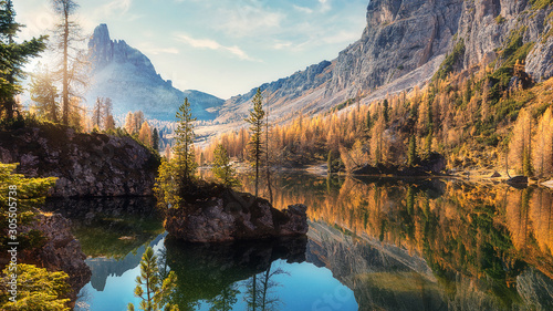 Amazing Federa lake, natural Scenery, during Sunrise. Awesome Landscape. Foggy Dolomites Alps with forest under sunlight. Travel in nature. Beautiful sunrise with Lake and majestic Mountains.