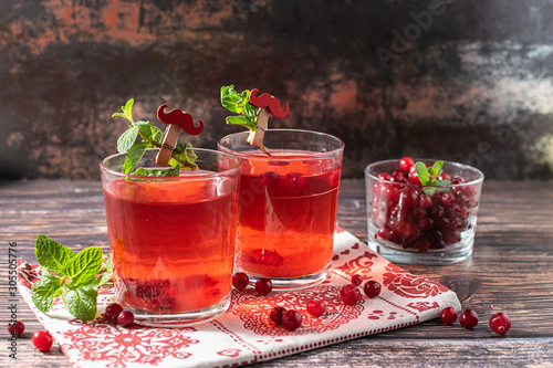 Two glasses of natural homemade non alcoholic cocktail with cranberries and mint on dark vintage background. Healthy vitamin drink.