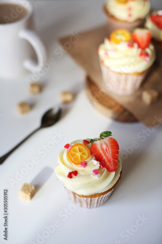 cupcake with cream cheese decorated with strawberries on a white background.