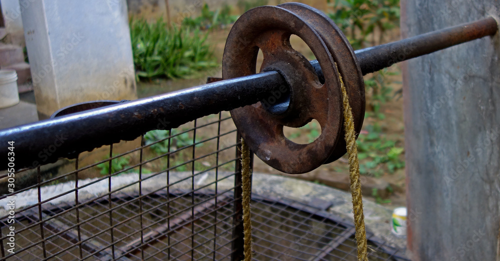 a rope on a iron made pully or wheel used to fetch water from a deep well in India close up. a rope on a iron made pully or wheel used to fetch water from a deep well in India close up.