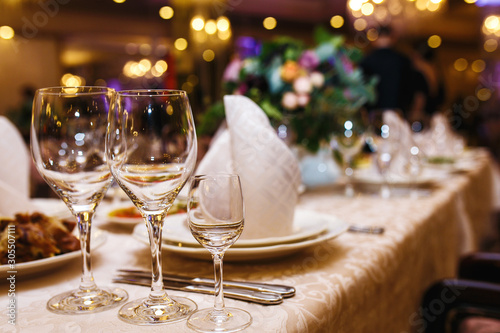 Serving wedding table. Sparkling glassware stands on long table prepared for wedding dinner. Banquet. 