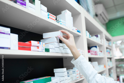 Bild auf Leinwand Closeup view of pharmacist hand taking medicine box from the shelf in drug store