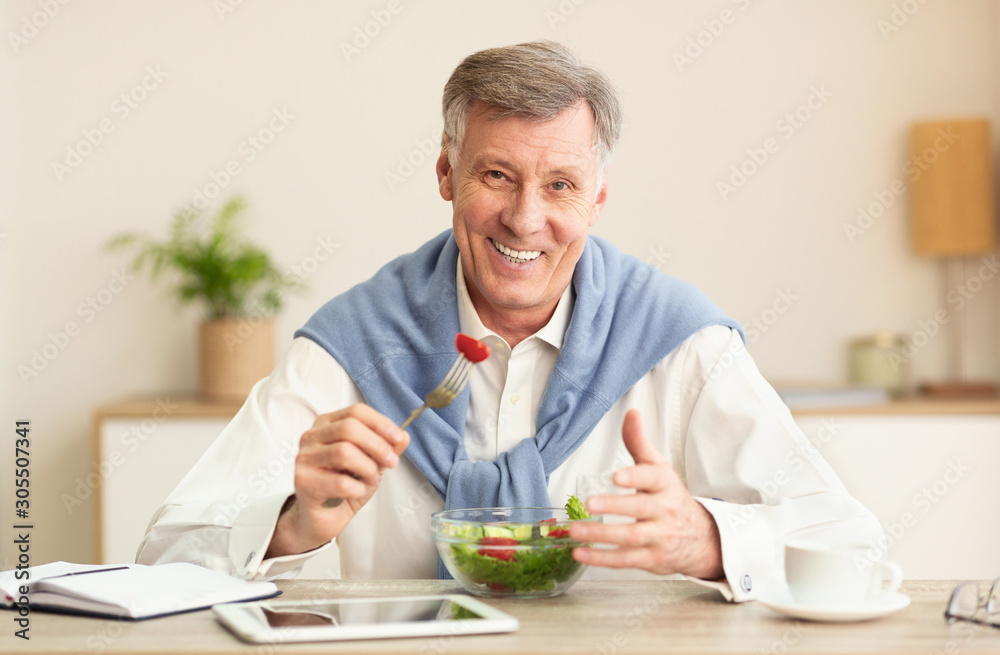 Senior Man Eating Vegetable Salad Smiling At Workplace Indoor