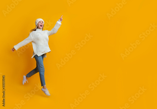 Excited winter girl running towards copy space
