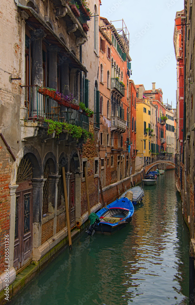 Picturesque city landscape of Venice. Shaming narrow canal with turquoise water and moored boats near buildings. Romantic and peaceful scene. Venice, Italy