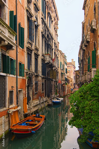 Romantic and peaceful scene of Venice city. Medieval buildings reflected in turquoise water. Boats moored along the buildings. Famous touristic place and romantic travel destination. Venice  Italy