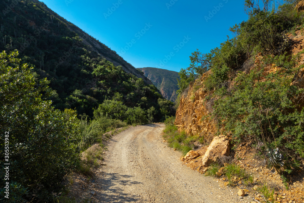 Gravel mountain pass through green valley