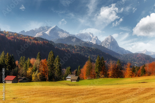 Awesome alpine highlands in sunny day. Sunny valley with Zugspitze mountain range and perfect sky on background. Beautiful autumn Landscape of Bavarian Alps, Germany, Europe.