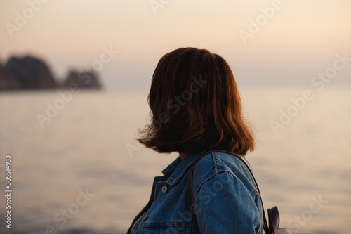 Closeup of anonymous woman looking something in the distance with wind in her hair. Woman on the beach with ocks - focus on the hair. Anonymous, no visible face.