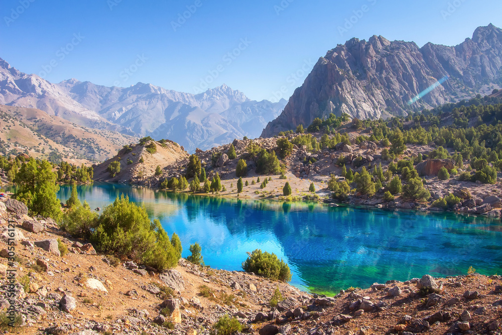 Scenic mountains nature landscape with blue lake on sunny day. Beautiful view on turquoise water on mountain valley. Alaudin lake in Fann mountains, Tajikistan