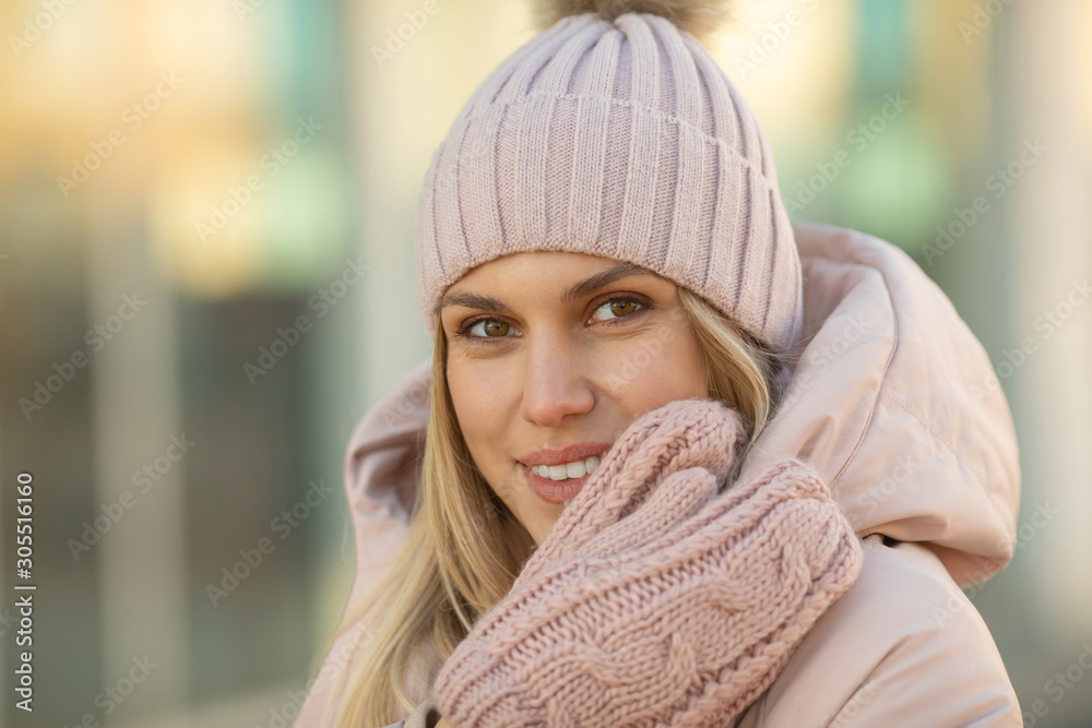 Portrait of a beautiful young model in pink knitted hat and mittens. Beautiful natural young smiling blonde woman wearing knitted gloves. Portrait of a beautiful young model in pink knitted hat and mittens. Beautiful natural young smiling blonde woman wearing knitted gloves.