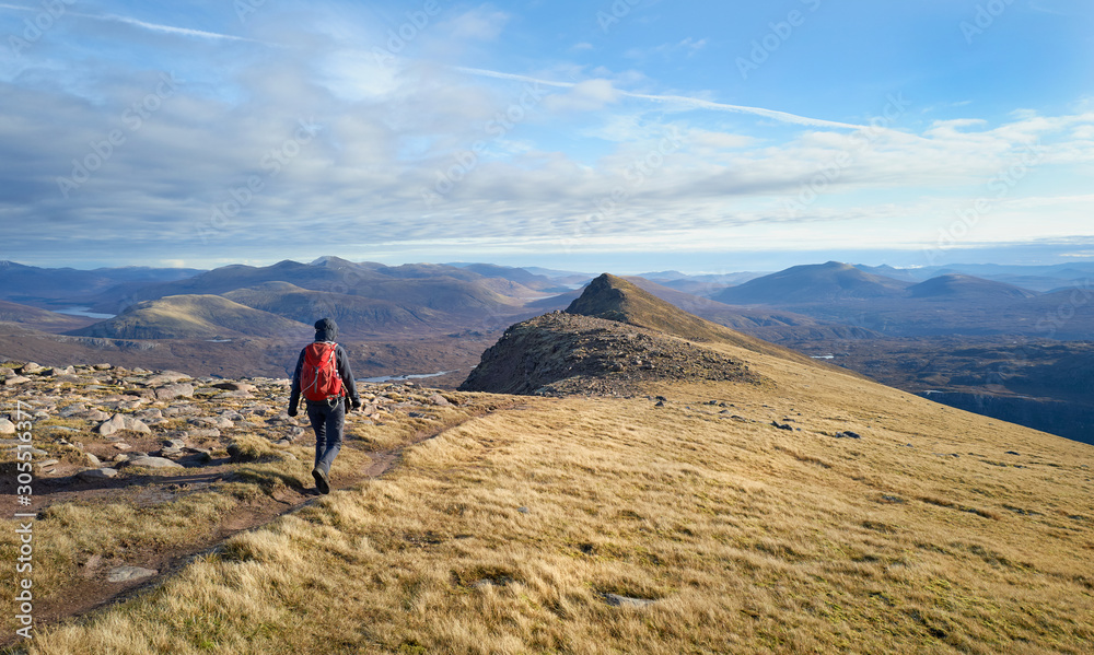 A closeup of a hiker wallking along the ridge from Slioch to the summit of Sgurr an Tuill Bhain in the Scottish Highlands.