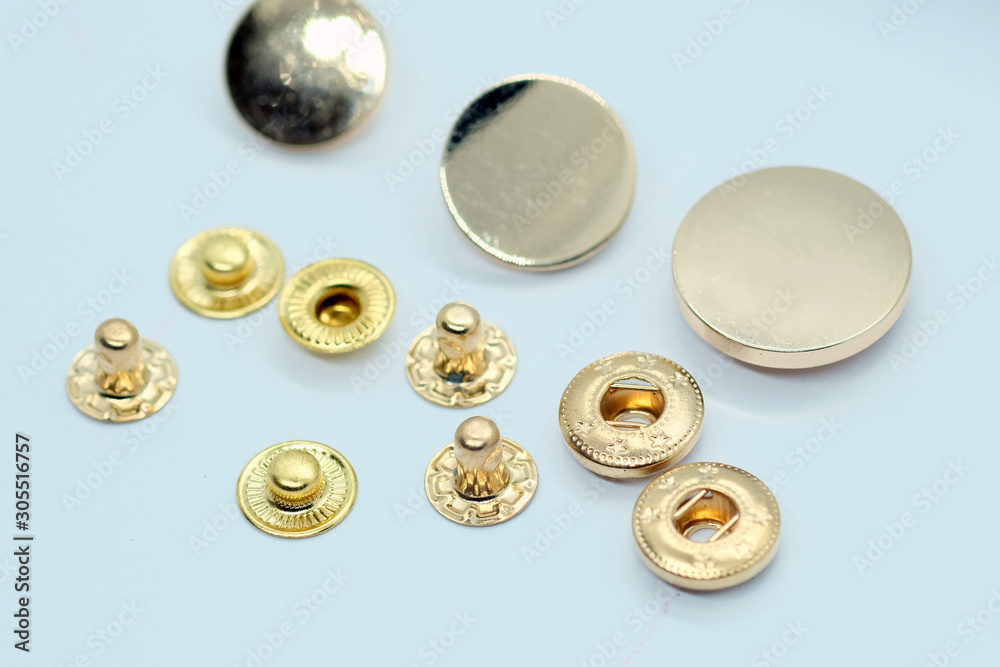 Metal button for clothes, gold color. Sewing accessories for outerwear production. Components of the press-stud with a flat top on a white background closeup.