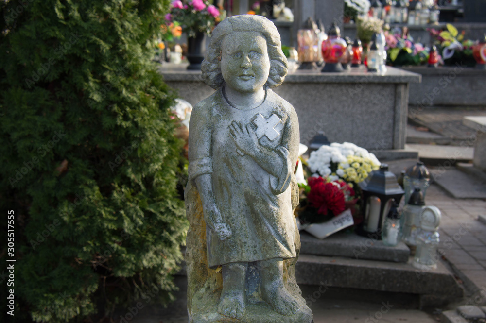 Monument and candles in the cemetery. All Saints Day in Poland. Stone sculpture.