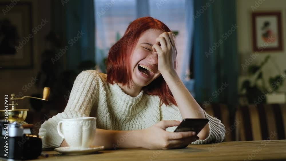 attractive teenager with smartphone sits at table with Cup of coffee in sweater. girl uses modern mobile phone to communicate and write messages. addiction. Mobile phones in daily life of a teenager attractive teenager with smartphone sits at table with Cup of coffee in sweater. girl uses modern mobile phone to communicate and write messages. addiction. Mobile phones in daily life of a teenager