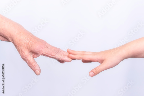 The hands of an old elderly grandmother and a child touch fingers in gestures on a white background. The concept of assistance, care and support for the elderly.