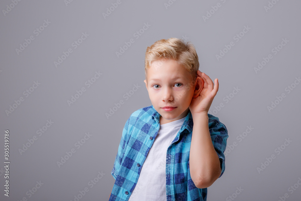 Portrait of little boy eavesdropping isolated on grey background Portrait of little boy eavesdropping isolated on grey background