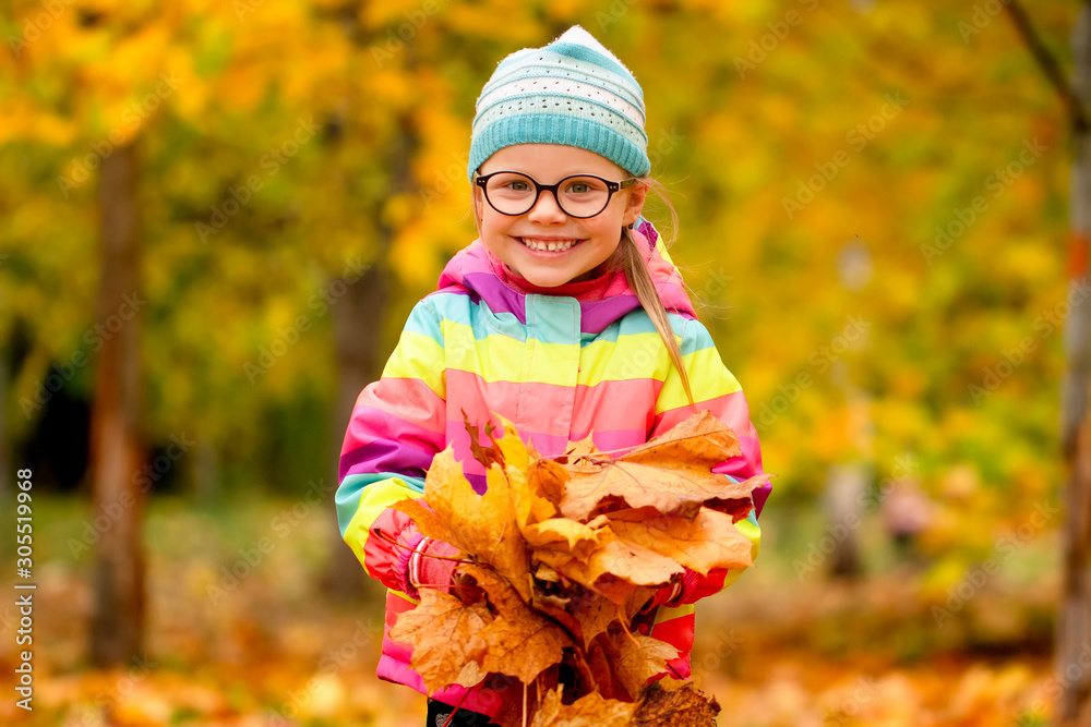 Autumn portrait of a little girl with yellow leaves in her hands in park Autumn portrait of a little girl with yellow leaves in her hands in park