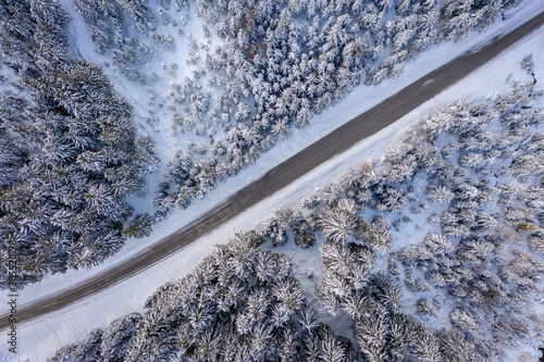 Aerial view of a snowy forest with high pines and road with a car in the winter. Stubaital, Tirol, Austria © Alexey Oblov