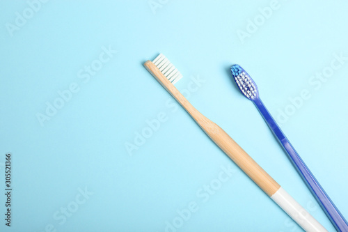 natural bamboo toothbrushes and plastic on a colored background top view.