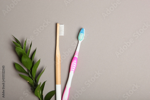 natural bamboo toothbrushes and plastic on a colored background top view.